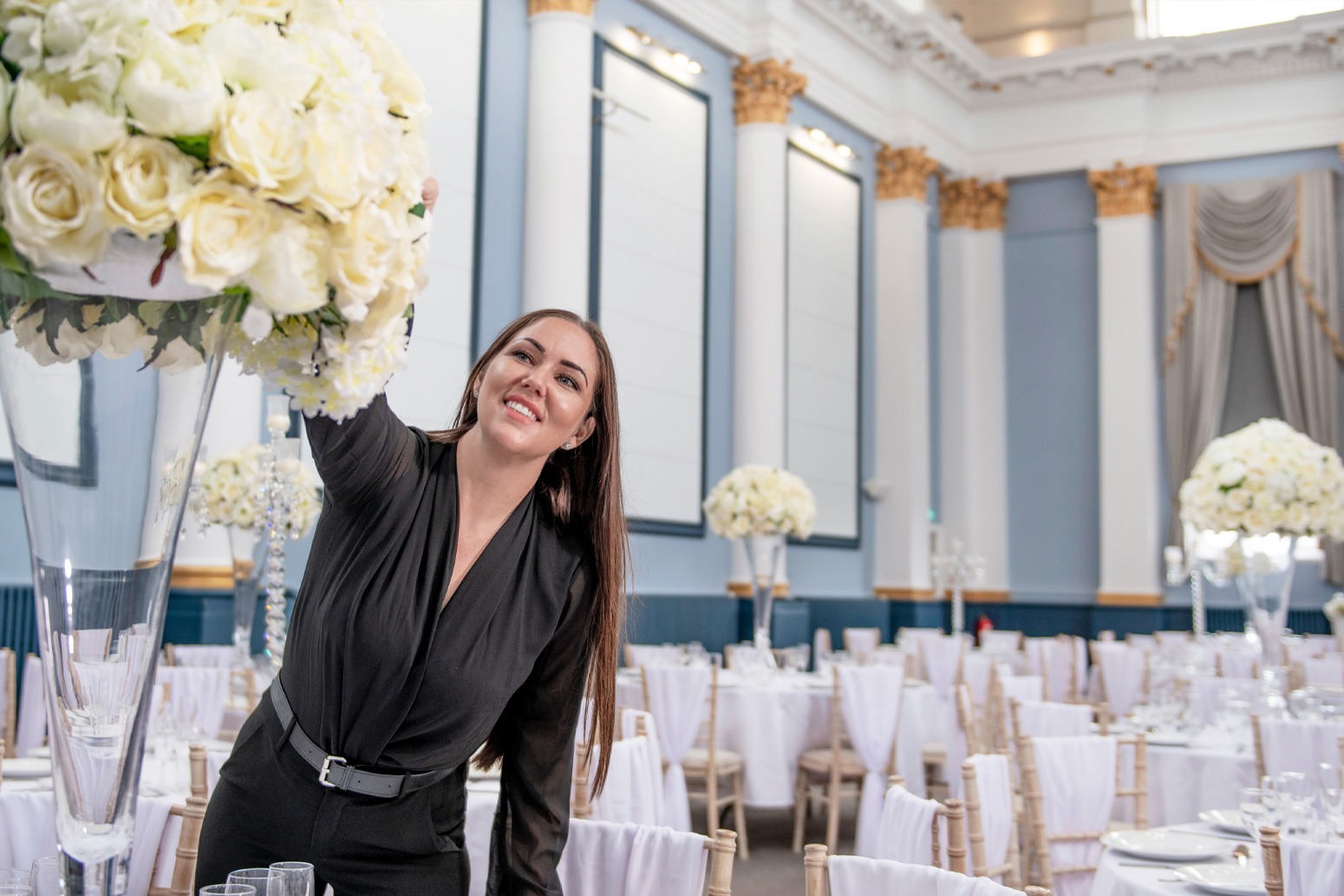 A staff member alters flowers.